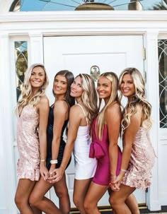 four beautiful young women posing for the camera in front of a white door wearing short dresses