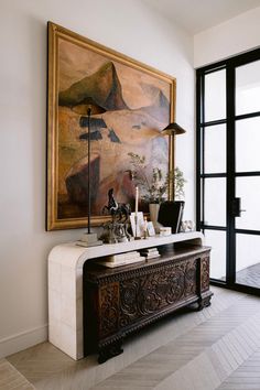 a living room with a painting on the wall and a table in front of it