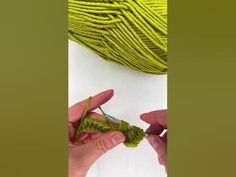 someone crocheting the ends of a ball of yarn with green yarn on it