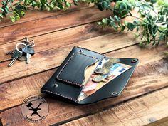 a wallet sitting on top of a wooden table next to a bunch of keys and money