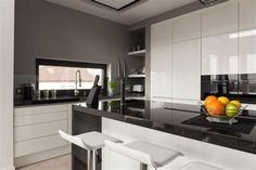 a bowl of fruit sitting on top of a black and white countertop in a kitchen