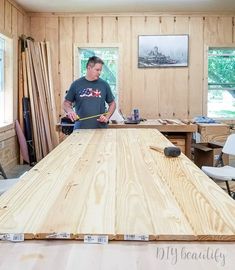 a man standing in front of a wooden table with tools on it and another man holding a hammer