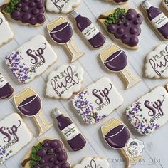 decorated cookies with wine and grapes are displayed on a white tablecloth for a celebration