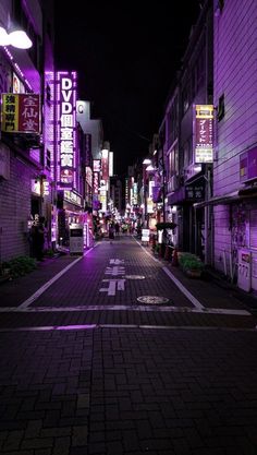 an empty city street at night with neon signs