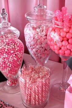 pink and white candies in large glass containers on a table with other candy items