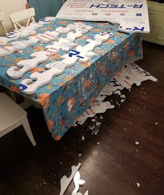 a table covered in dog bone cutouts on top of a hard wood floor next to white chairs