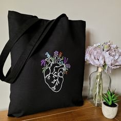 a black tote bag sitting on top of a wooden table next to a potted plant