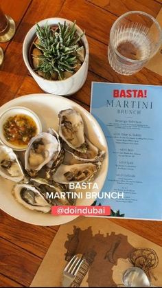 a table topped with plates of oysters next to glasses of wine and silverware