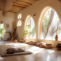 a room with three arched windows and floor pillows on the floor in front of them