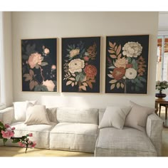 three floral paintings hang on the wall above a couch