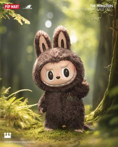 a small stuffed animal is standing in the middle of a forest with trees and grass