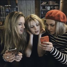 three women are looking at their cell phones