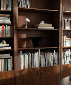 a bookshelf filled with lots of books next to a lamp