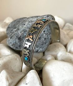 "This beautiful Tibetan silver cuff bracelet is made in Nepal. Size: 18cm - As It's open-ended, would fit most hands Width - 15mm approx Weight - 23 gms approx Material: white metal, copper, brass To fit the bracelet open it up so the gap is wide enough to pass over the narrowest part of your wrist and then squeeze it back into shape until it is a nice comfortable fit. Meaning \"Om Mane Padmi Aum\":  This mantra means \" jewels of the lotus \". It is said that it was given to us by all the buddh Buddhist Bracelet, Om Mani Padme Hum, Open Ended, Copper Brass, Bracelet Bangle, Spiritual Jewelry, Silver Cuff Bracelet, Silver Cuff, The Gap