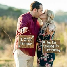 a man and woman kissing in front of a sign that says i stole her heart so i'm stealing his last name