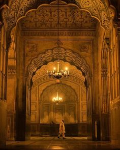 a person standing in an ornate building with chandeliers