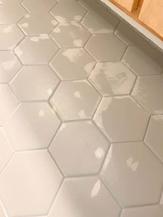 a kitchen floor with white tiles and wooden cabinets