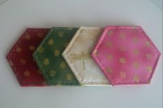 four different colored hexagons with gold and pink designs on them, all lined up in a row