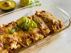 a casserole dish with meat, cheese and avocado on the side