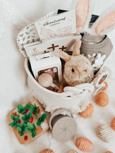 a basket filled with lots of items on top of a white bed covered in shells