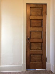 an empty room with a wooden door and carpet