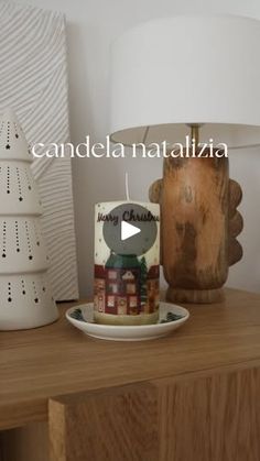 a wooden table topped with a white lamp next to a plate and candle holder on top of it