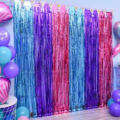 a room filled with balloons and streamers next to a wall covered in tinsel