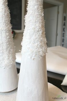 two tall white vases sitting on top of a table