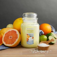 an orange and grapefruit candle surrounded by citrus fruit