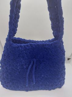 a blue handbag sitting on top of a white table next to a toilet paper roll