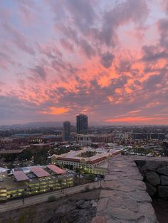 the sun is setting over a city with tall buildings