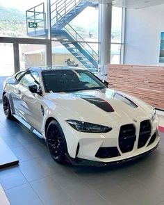 a white sports car parked in a showroom with stairs leading up to the door