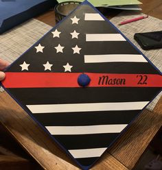 a person is holding up a thin red line flag with the name mason 22 on it