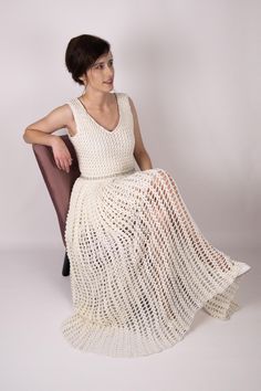 a woman sitting in a chair wearing a white crochet dress