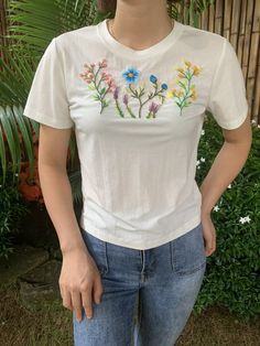 a woman wearing a white t - shirt with colorful flowers on the front and side