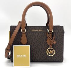 Brand New With Tag Michael Kors Sheila Small Satchel Shoulder Crossbody Bag Vegan Leather Gold Toned Hardware Color: Brown 100% Authentic **Please See The Measurement For The Size** No Dust Bag Michael Kors Logo At Front 1 Mk Charm Zip Top Closure Triple Compartment With Center Zip Custom Fabric Lining 1 Slip-In Pocket 9" (Bottom) X 6.5"(H) X 3"(D) Straps: 3.5" Adjustable Strap: 20.25"-23.75" Bag Michael Kors, Michael Kors Satchel, Michael Kors Logo, Leather Satchel Handbags, Satchel Tote Bag, Michael Kors Shoulder Bag, Luxury Bag, Satchel Tote, Black Leather Bags