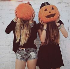 two girls holding pumpkins up to their faces