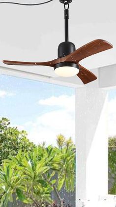 a ceiling fan that is hanging from the ceiling in front of a window with palm trees