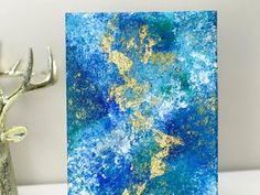 a blue card with gold foil on it next to a silver deer statue and white wall