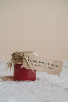 a jar of jam with a tag that says spread the love strawberry jam on it