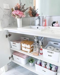 a white bathroom sink sitting under a mirror next to a shelf filled with toiletries