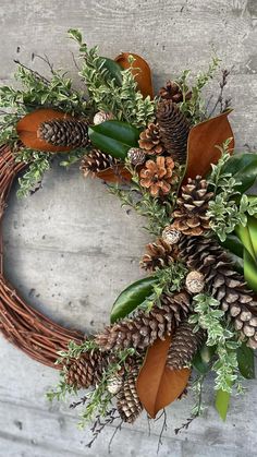 a wreath with pine cones and greenery