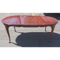 an oval wooden table sitting on top of a parking lot with no one around it