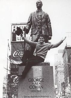 a black and white photo of a man standing in front of a statue with his arms outstretched