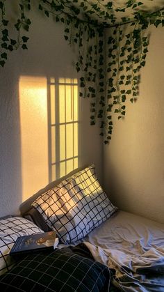 a bed with two pillows and some ivy growing on the wall above it, next to a window