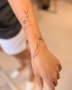 a woman's arm with a small flower tattoo on the left side of her wrist