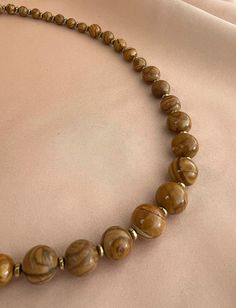 Looks like wood, but it is a gemstone. 19.5 inch sits just below the collarbone. Naturally occurring mineral deposits form the unique wood-like appearance. Jasper is worn to attract financial success, instill calm, and increase inner strength and stability in challenging situations. Hematite is protective; it repels negativity and evil eye. 4, 6, 8, and 10mm Scene Jasper, 4mm hematite spacers, Gold Finished Brass S-hook clasp. Handcrafted and designed by resident artist Delhi Pietrala, exclusively for Chez Monkay.  With drawstring bag and Chez Monkay tag, for gifting or keeping. Free shipping. Brown Gemstone Beads Nature-inspired Necklace, Nature-inspired Brown Gemstone Bead Necklace, Earthy Brown Necklaces For Healing, Brown Agate Necklace For Healing, Brown Agate Necklaces With Polished Beads, Brown Necklace With Natural Variations For Gifts, Elegant Brown Agate Necklaces, Elegant Brown Agate Necklace, Brown Jasper Gemstone Bead Necklaces