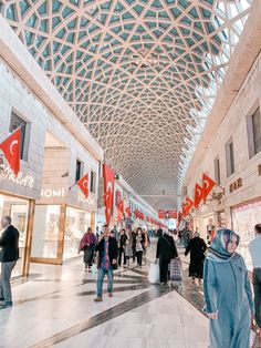 many people are walking around in the shopping mall with red flags hanging from the ceiling