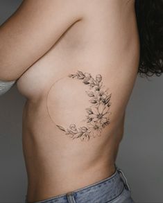 a woman's breast with flowers and leaves on her side, showing the lower part of