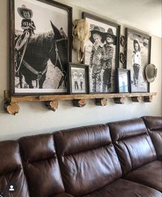 a living room filled with brown leather couches and pictures on the wall above them